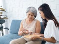 Portrait of Asian senior woman grey short hair holds pill and a glass of drinking water from young adult daughter. Royalty Free Stock Photo