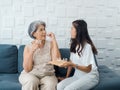 Portrait of Asian senior woman grey short hair holds pill and a glass of drinking water from young adult daughter. Royalty Free Stock Photo