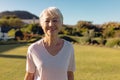 Portrait of asian senior woman with short hair standing on grassy land against clear sky in yard Royalty Free Stock Photo