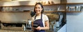 Portrait of asian smiling female barista, cafe waitress holding cup of coffee, serving clients, taking order to the Royalty Free Stock Photo