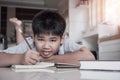 Portrait Asian Student boy elementary lay doing his homework on notebook while learning study at home and looking camera with Royalty Free Stock Photo