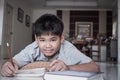 Portrait Asian Student boy elementary lay doing his homework on notebook while learning study at home and looking camera with Royalty Free Stock Photo