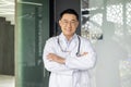 Portrait of Asian successful head doctor of clinic, man in white medical coat with stethoscope smiling and looking at Royalty Free Stock Photo