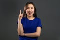 Portrait of asian thinking woman having idea moment pointing finger up on grey studio background. Smiling happy girl Royalty Free Stock Photo