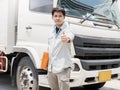 Portrait of Asian a truck driver looking with giving thumb-up and a white truck. Royalty Free Stock Photo