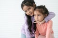 Portrait of Asian two sisters, 6 year and 3 year old, in casual clothes with black long hairs. Cute little girl smiling embracing Royalty Free Stock Photo