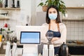 Portrait of Asian waitress stand with confident and cross arm in cafe. Attractive young beautiful girl barista in apron wear mask Royalty Free Stock Photo