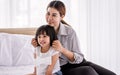 Portrait Asian warm family, mother, daughter playing together, hugging on white bed in comfortable bedroom at home with love and Royalty Free Stock Photo