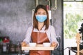 Portrait of Asian woman barista wearing face mask working in coffee shop Royalty Free Stock Photo