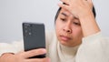 Portrait of Asian woman holding mobile phone, reading bad message, feeling sad and crying. Upset young woman sitting at home Royalty Free Stock Photo
