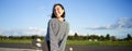 Portrait of asian woman with longboard. Korean girl skating, holding skateboard in hands, posing on road, smiling and Royalty Free Stock Photo