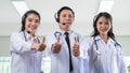 Portrait of Asian woman and man doctor with headset and stethoscope, thumbs up standing with computer to advice medicines or Royalty Free Stock Photo