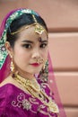 Portrait Asian woman in a margenta Indian tradition sari, she is looking at a camera next to the an orange wall