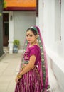 Portrait Asian woman in a margenta Indian tradition sari, she is looking at a camera next to the white wall