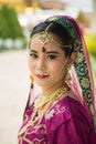 Portrait Asian woman in a margenta Indian tradition sari, she is looking at a camera next to the white wall