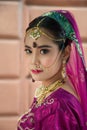 Portrait Asian woman in a margenta Indian tradition sari, she is looking at a camera next to the white wall