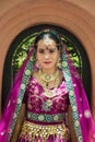 Portrait Asian woman in a margenta Indian tradition sari, she is looking at a camera with orange wall background