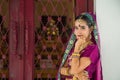 Portrait Asian woman in a margenta Indian tradition sari, she is looking at a camera touching her chin by her hand in front of a