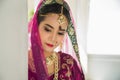 Portrait Asian woman in a margenta Indian tradition sari, she is looking down at side a white wall