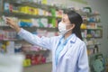 Portrait of asian woman pharmacist wearing a surgical mask in a modern pharmacy drugstore, covid-19 and pandemic concept Royalty Free Stock Photo