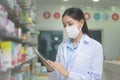 Portrait of asian woman pharmacist wearing a surgical mask in a modern pharmacy drugstore, covid-19 and pandemic concept Royalty Free Stock Photo