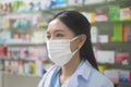 Portrait of asian woman pharmacist wearing a surgical mask in a modern pharmacy drugstore, covid-19 and pandemic concept Royalty Free Stock Photo