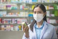 Portrait of asian woman pharmacist wearing a surgical mask in a modern pharmacy drugstore, covid-19 and pandemic concept Royalty Free Stock Photo