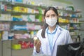 Portrait of asian woman pharmacist wearing a surgical mask in a modern pharmacy drugstore, covid-19 and pandemic concept Royalty Free Stock Photo