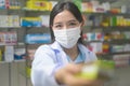 Portrait of asian woman pharmacist wearing a surgical mask in a modern pharmacy drugstore, covid-19 and pandemic concept Royalty Free Stock Photo