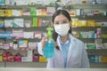 Portrait of asian woman pharmacist wearing a surgical mask using alcohol gel in a modern pharmacy drugstore, covid-19 and pandemic Royalty Free Stock Photo