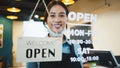 Portrait of Asian woman restaurant or coffee shop owner smile, hanging open sign post