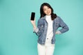 Portrait of Asian woman showing or presenting mobile phone application over green background.