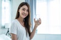 Portrait of Asian woman sit on bed, hold a glass of water in bedroom. Young thirsty attractive beautiful girl hold clean mineral