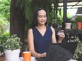 Asian woman sitting at table in garden, using credit card and laptop for online shopping., smile, fresh and happy feeling in the