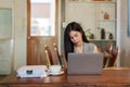 Portrait, asian woman sitting working in cafe, there is laptop computer in foreground large pile documents, was busy with pile