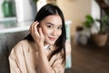 Portrait of asian woman smiling, sitting at home. GIrl touches her hair and looks cute at camera Royalty Free Stock Photo