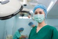 Portrait of Asian woman surgeon with medical mask standing in operation theater at a hospital. Team of Professional surgeons. Royalty Free Stock Photo