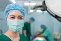 Portrait of Asian woman surgeon with medical mask standing in operation theater at a hospital. Team of Professional surgeons. Royalty Free Stock Photo