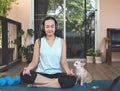 Asian woman wearing headphones, practice meditation on yoga mat in balcony  with computer laptop  and Chihuahua dog. Yoga or Royalty Free Stock Photo