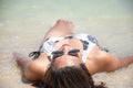 Portrait of Asian woman wearing white swimsuit and wear sunglasses lying on a sandy beach Royalty Free Stock Photo