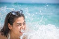 Portrait of Asian woman wearing white swimsuit and wear sunglasses lying on a sandy beach and water splashes Royalty Free Stock Photo