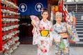 Portrait of Asian women wear japanese style dress with hold multicolor fan and stand in front of small shop and look happiness Royalty Free Stock Photo