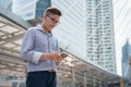 Portrait of asian young businessman standing at Outside Office. Young businessman wear suit smiling and looking at smartphone Royalty Free Stock Photo