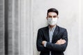 Portrait of Asian Young Businessman Wearing Surgical Mask and standing at the Wall, Smiling and Crossed Arms