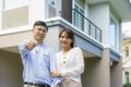 Portrait of Asian young couple standing and hugging together and holding house key looking happy in front of their new house to Royalty Free Stock Photo