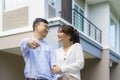 Portrait of Asian young couple standing and hugging together and holding house key looking happy in front of their new house to Royalty Free Stock Photo