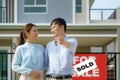 Portrait of Asian young couple standing and hugging together and holding house key looking happy in front of their new house to Royalty Free Stock Photo