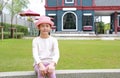 Portrait of Asian young girl child wearing pink straw hat sitting in the garden Royalty Free Stock Photo