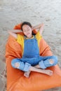 Portrait of Asian young girl in dungarees jean relax and sleeping on orange sofa bed beach on sand at summer holiday Royalty Free Stock Photo