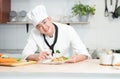 Portrait of Asian young handsome chef man wear white chef uniform, holding food forceps to garnish spaghetti dish, working at rest Royalty Free Stock Photo